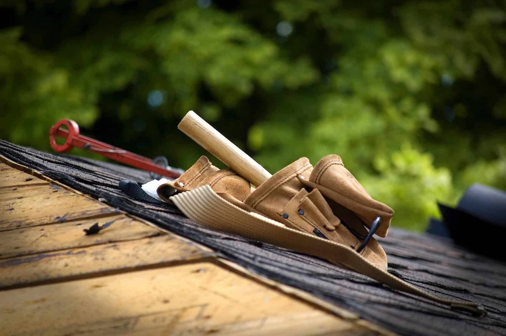 A tool belt with a hammer and other tools on a wooden rooftop, essential for roof repair in Central Illinois.