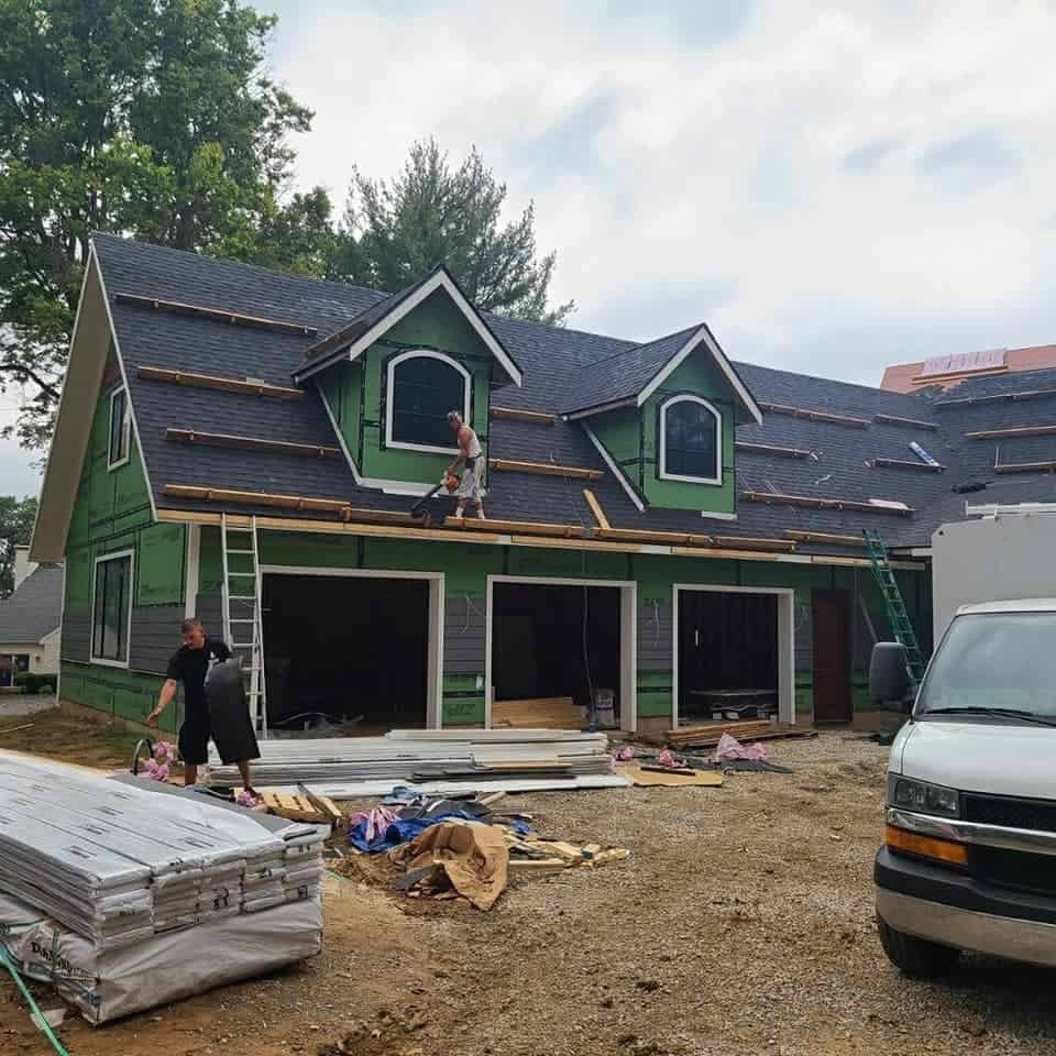 House under construction with roof contractors installing exterior elements.