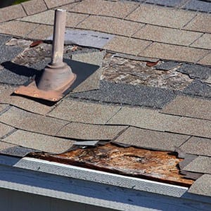 Damaged Central Illinois roofing with missing shingles and exposed, weathered plywood.